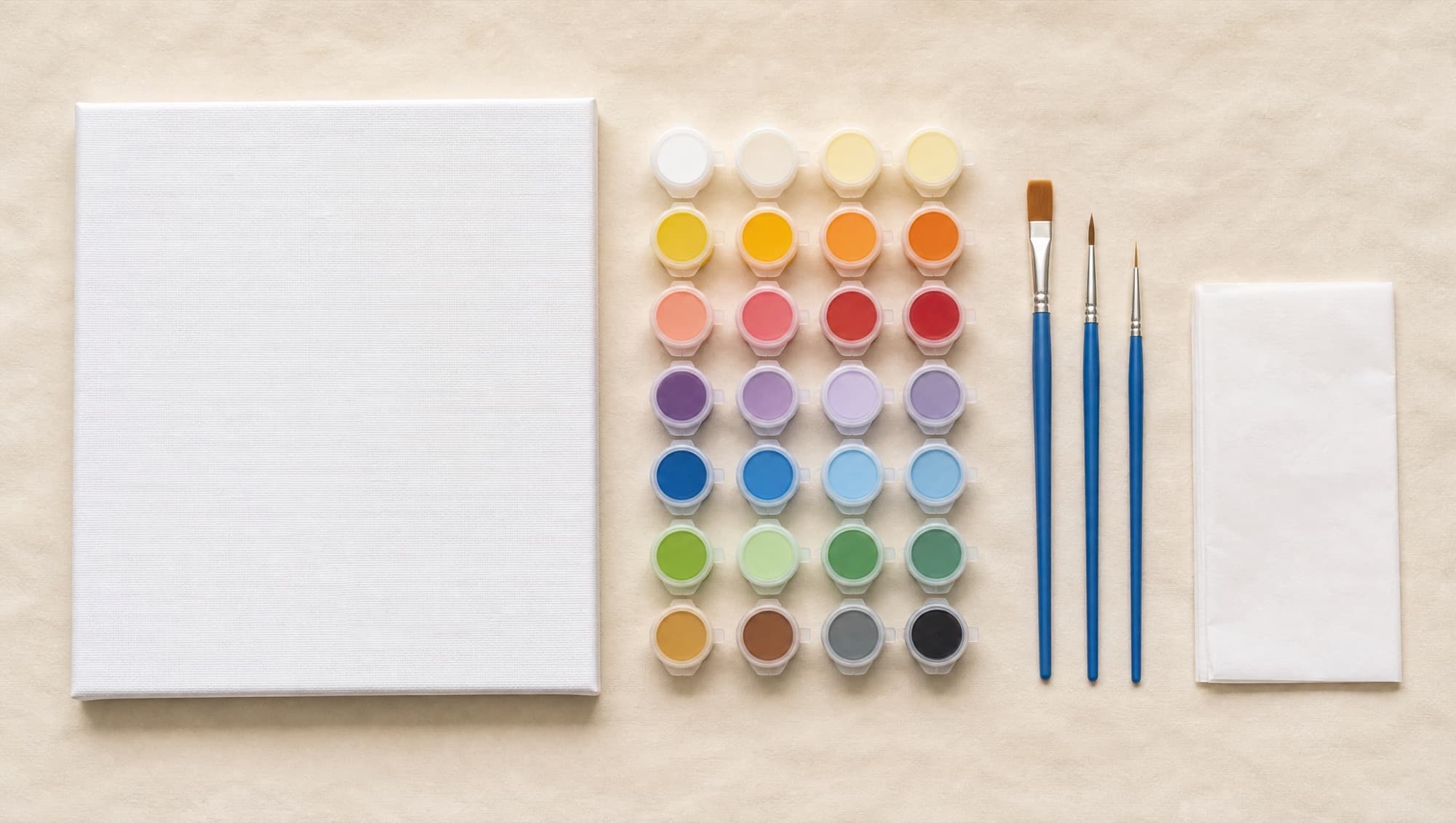 A paint-by-numbers kit laid out on cotton paper: blank canvas, paint pots and brushes